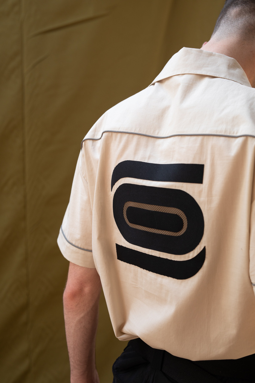 A model wearing a beige logoed shirt from Olly Shinder's CSM graduate collection