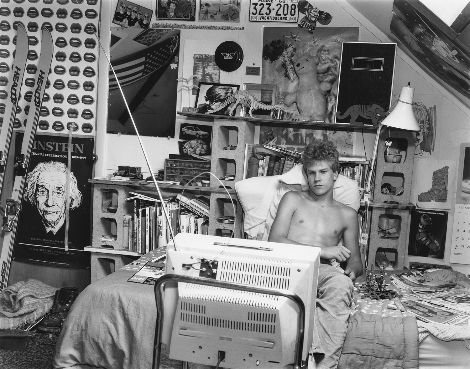 a young model watches tv in his room