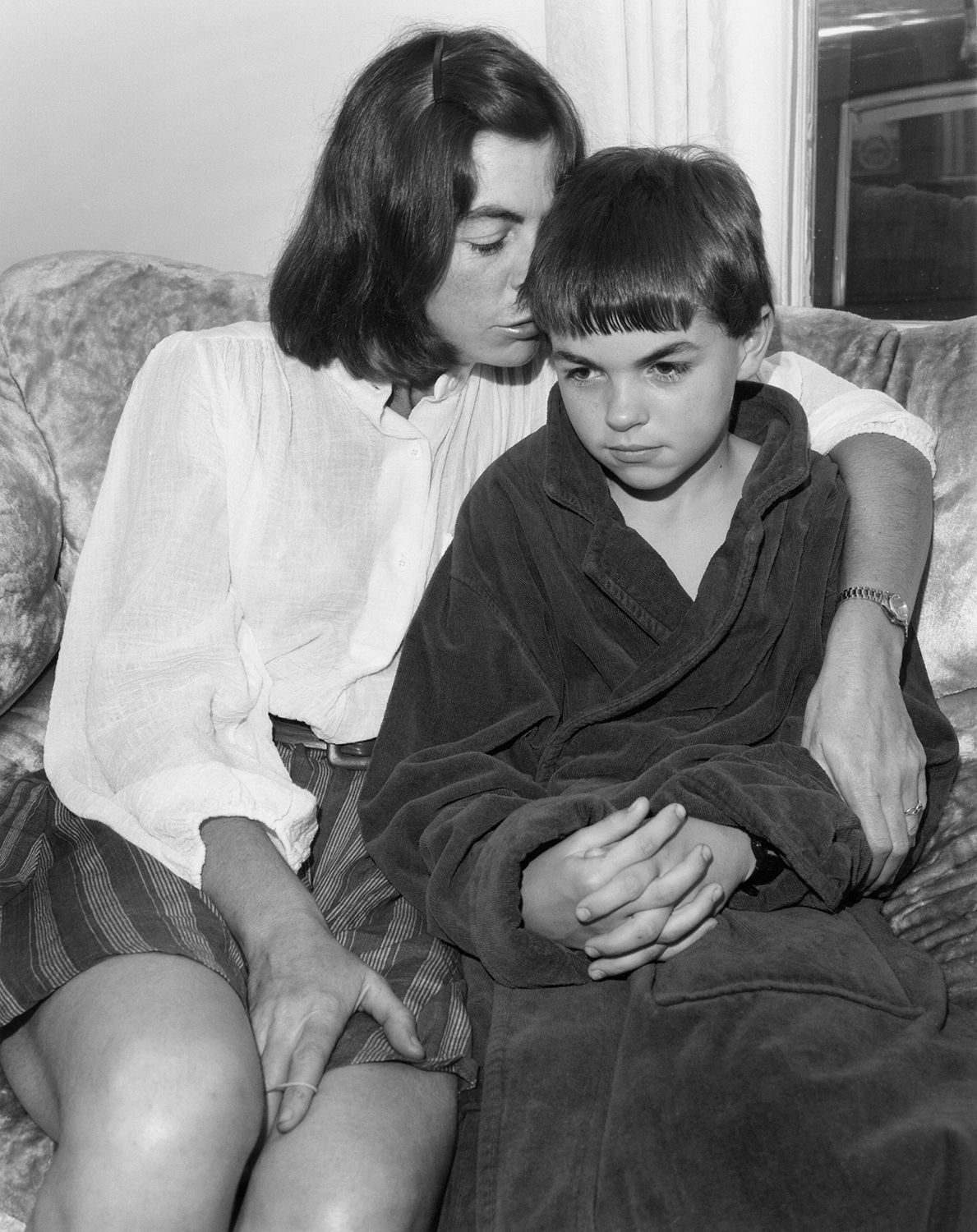 a woman sits with her arm around a young child