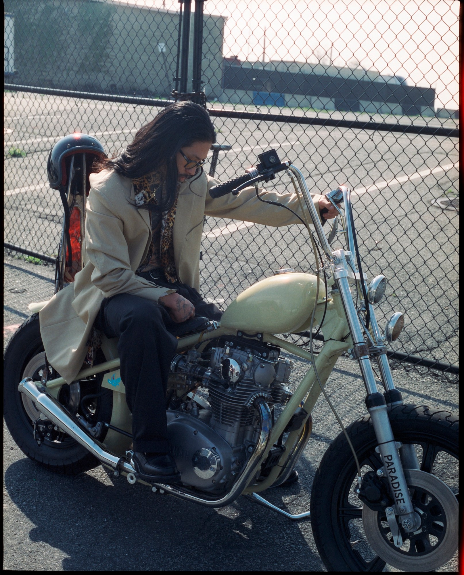 jae kim posing on a motorcycle in front of a chain link fence