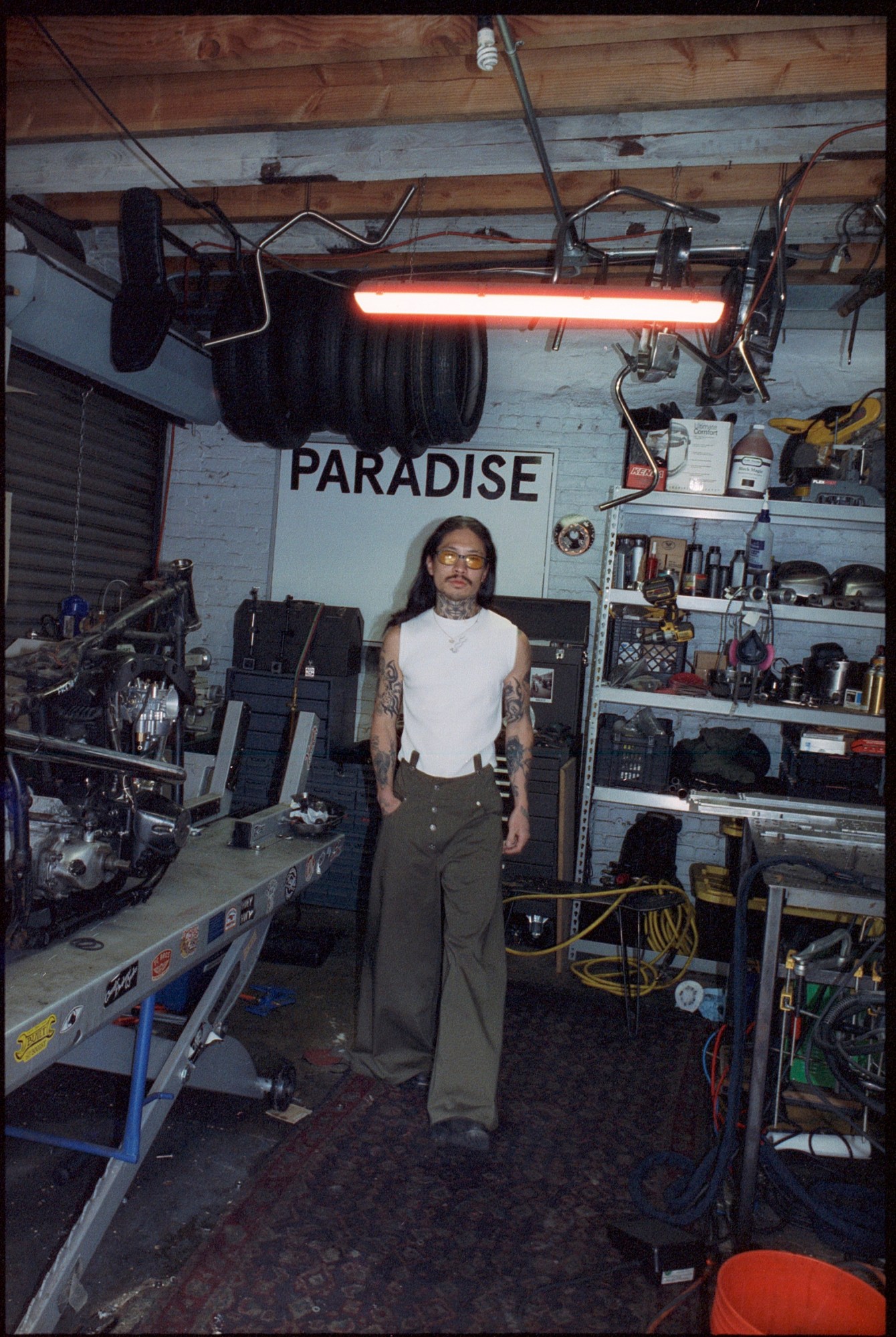 jae kim walking in a garage in front of tools and a sign that says paradise