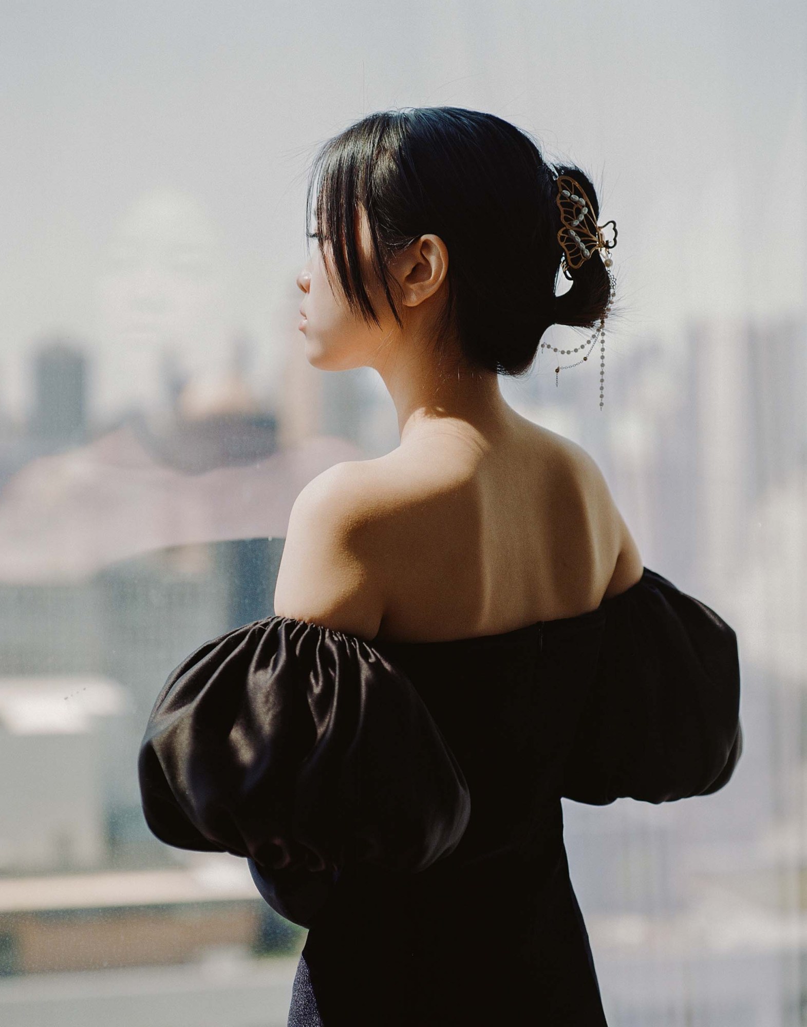 a girl in a black dress with puffy sleeves staring out the window