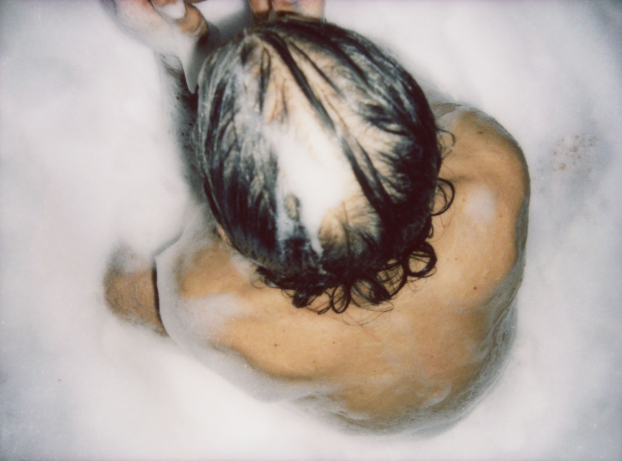 crown of a man's head seen from above in a soapy bath