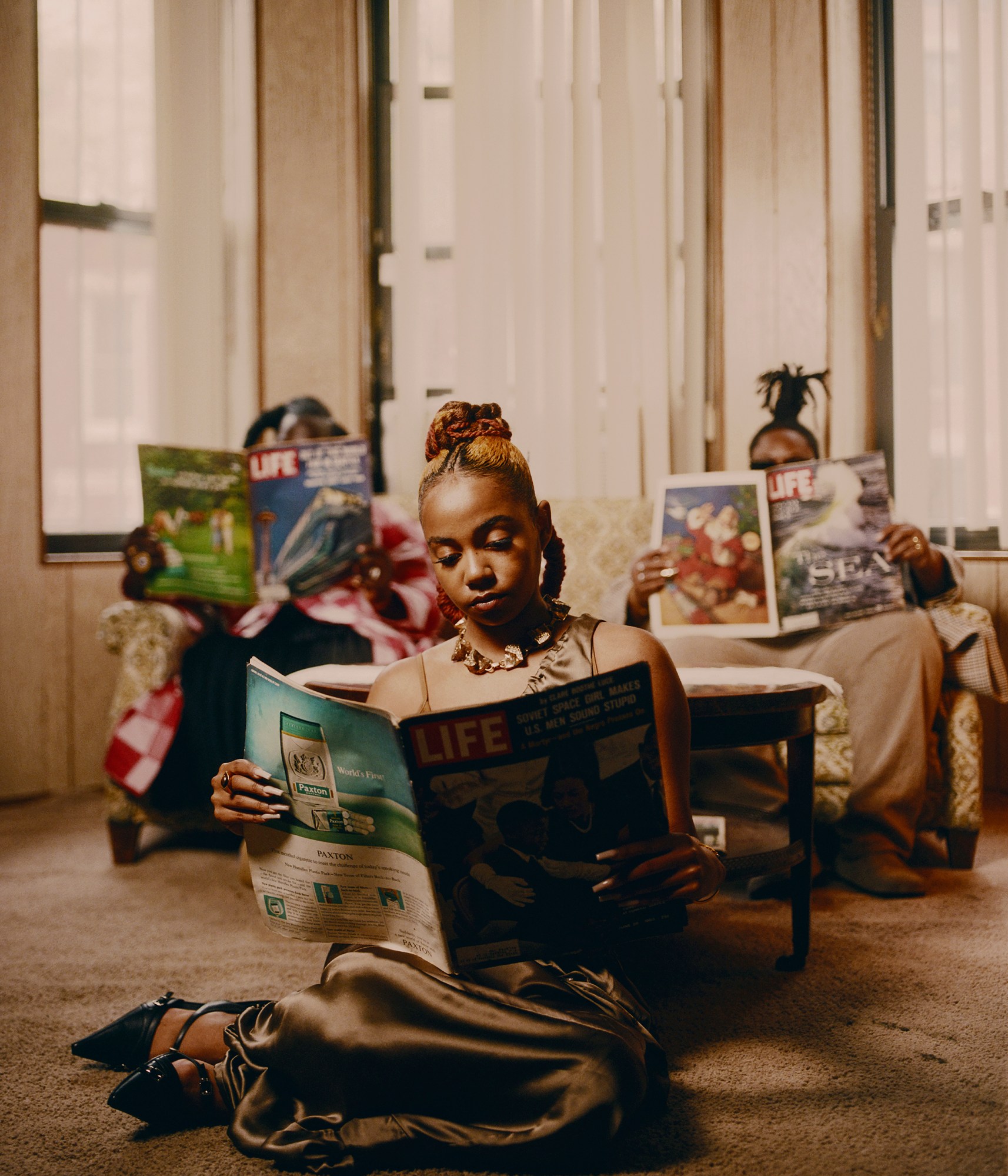 three black women sitting in their living room reading life magazine photographed by kendall bessent for chucha studios