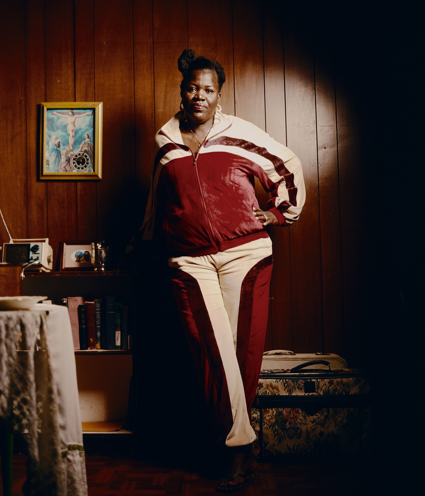 a woman wearing a red and white velour tracksuit in front of a wooden wall photographed by kendall bessent for chucha studios