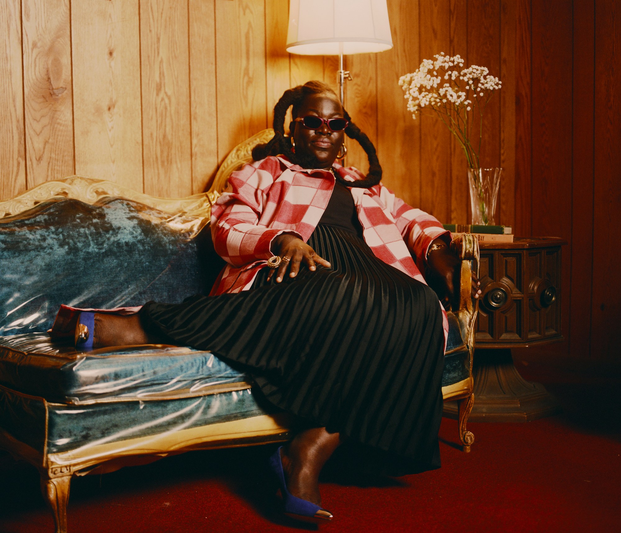 a woman wearing sunglasses sitting on a colorful couch photographed by kendall bessent for chucha studios