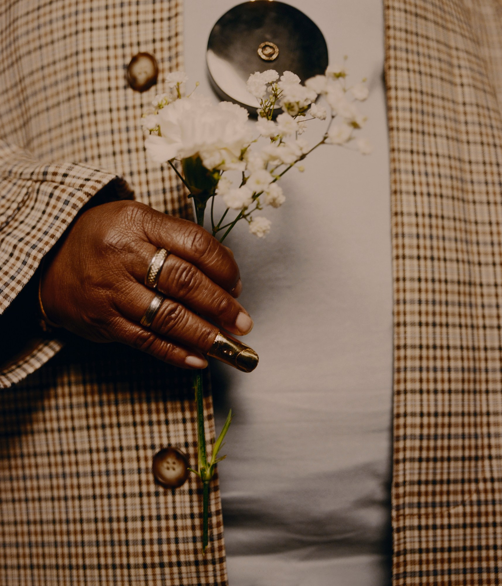 a close up of a hand holding wildflowers and wearing gold rings photographed by kendall bessent for chucha studios