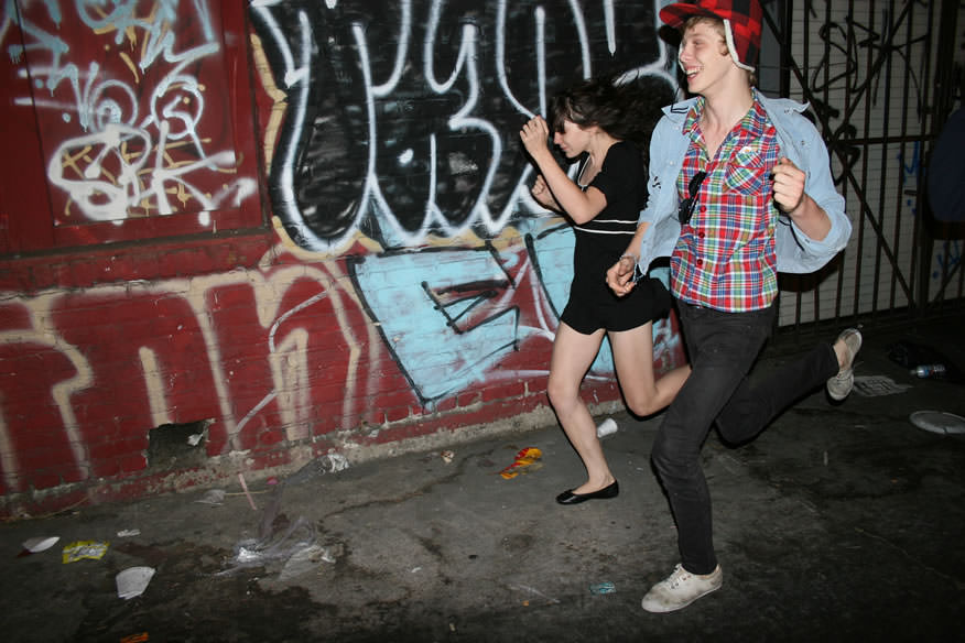 two people running down the street in williamsburg in the 2000s photographed by the cobrasnake