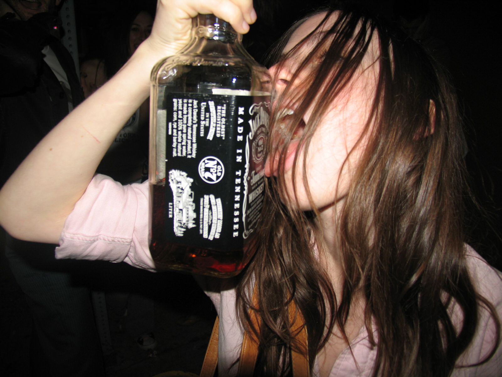 a girl with messy hair licking a jack daniels bottle photographed by the cobrasnake