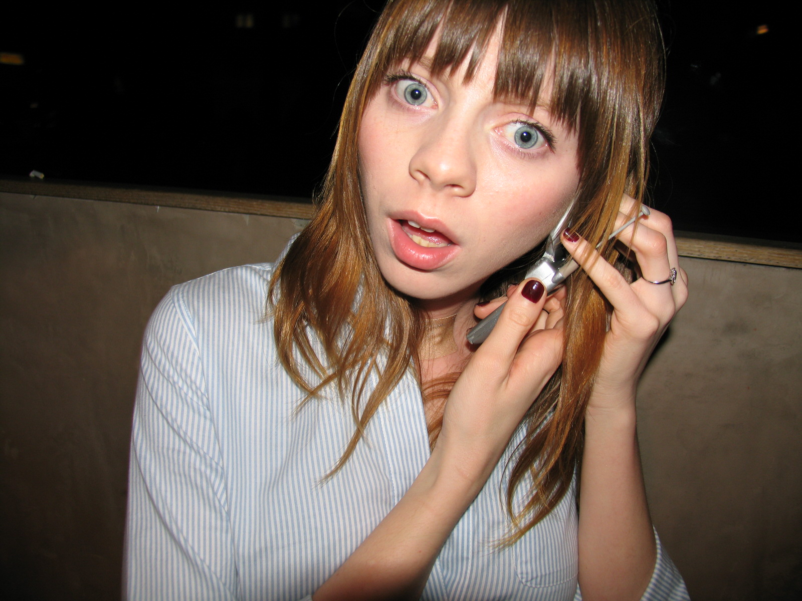 a wide-eyed girl using a flip phone photographed by the cobrasnake