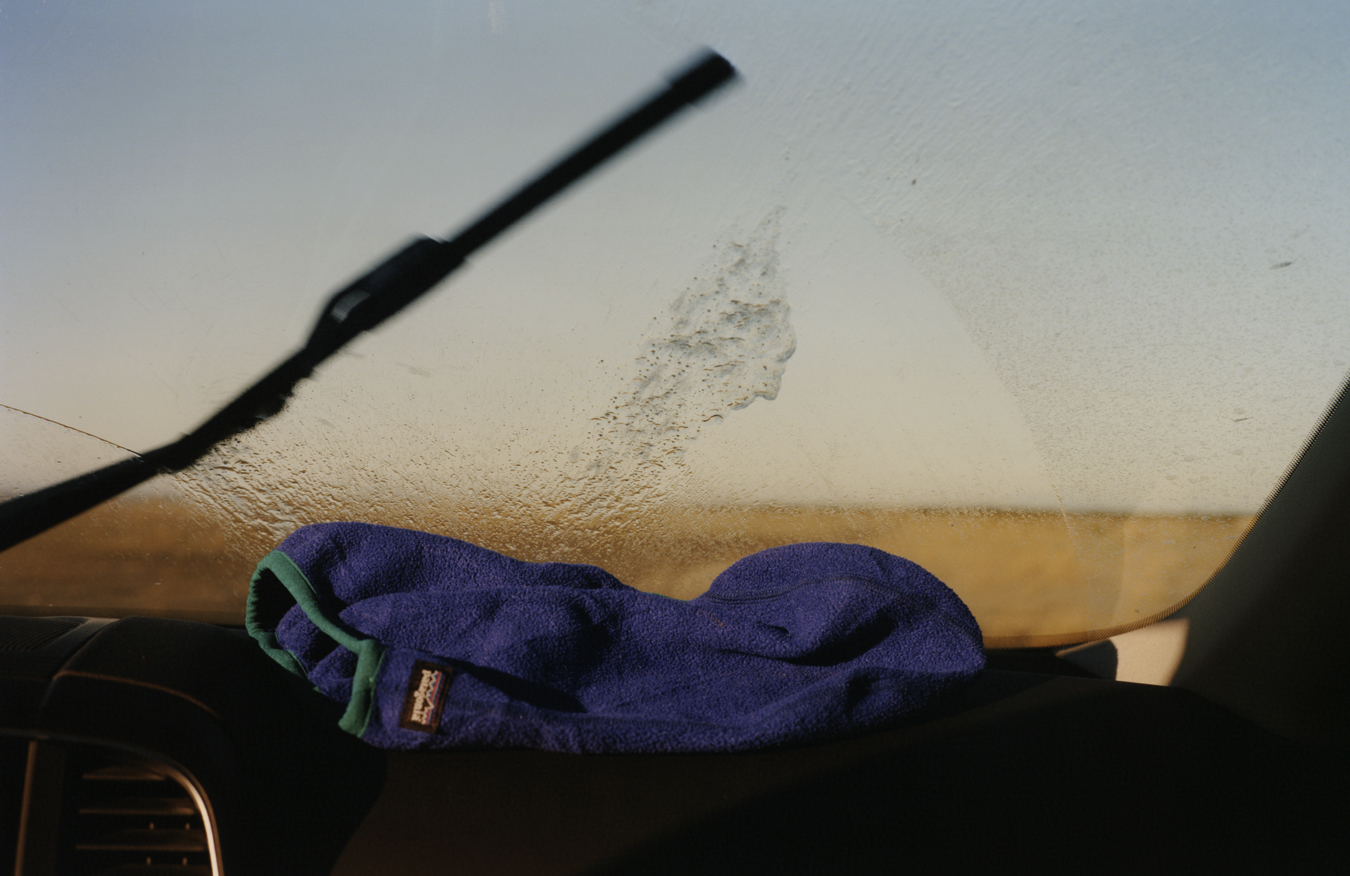 A Patagonia top on a car front window sill as windscreen wipers wash away a dirty window.