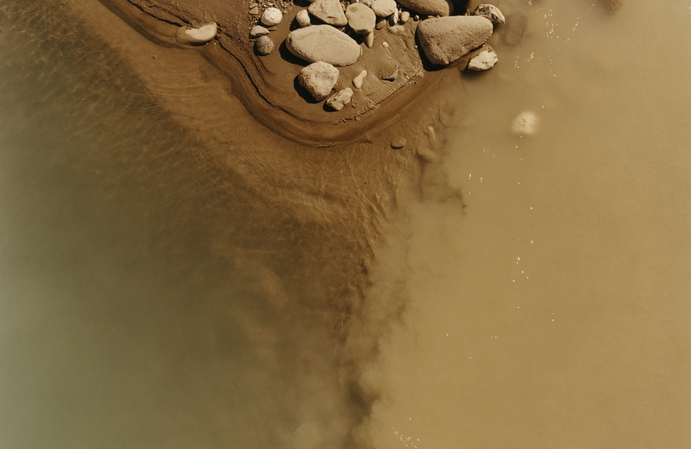 close up of the sand and rock meeting the water of the river Vjosa in Albania