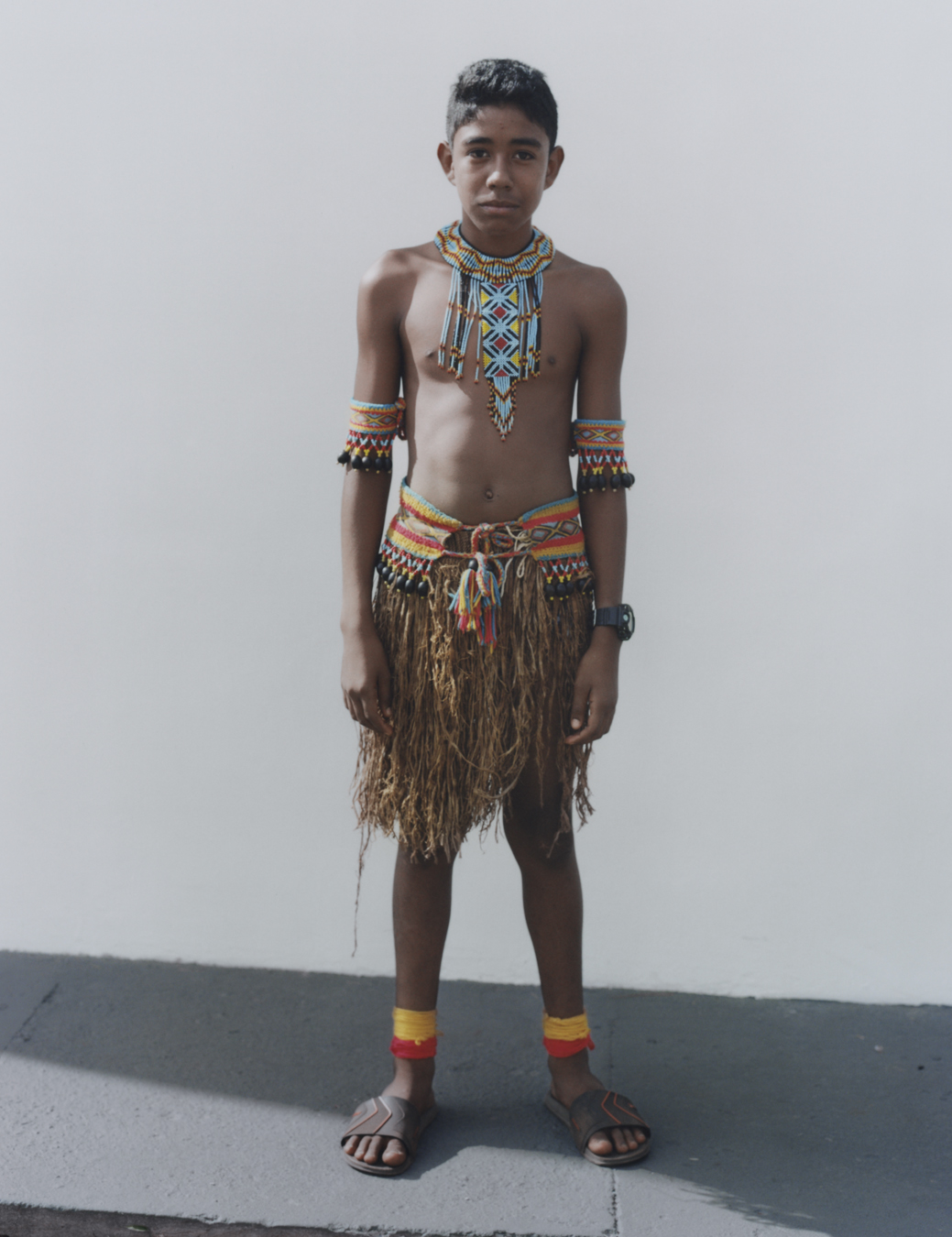 protester wearing traditional indigenous clothing standing against a wall