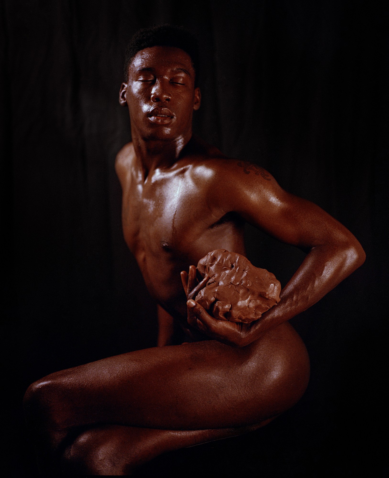 Naked man holding a mound of clay.