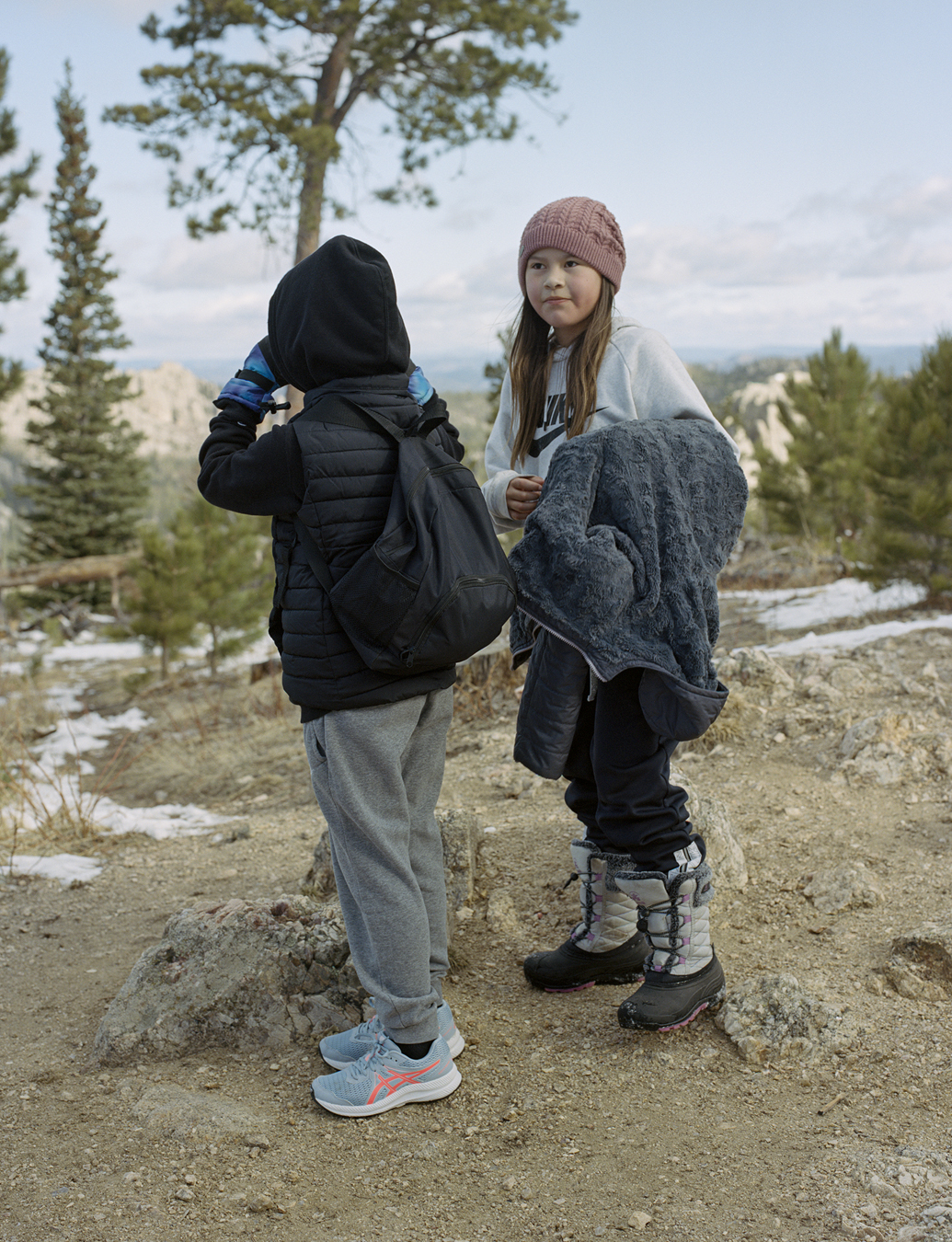 Two children from the local indigenous community hiking through an icy forest