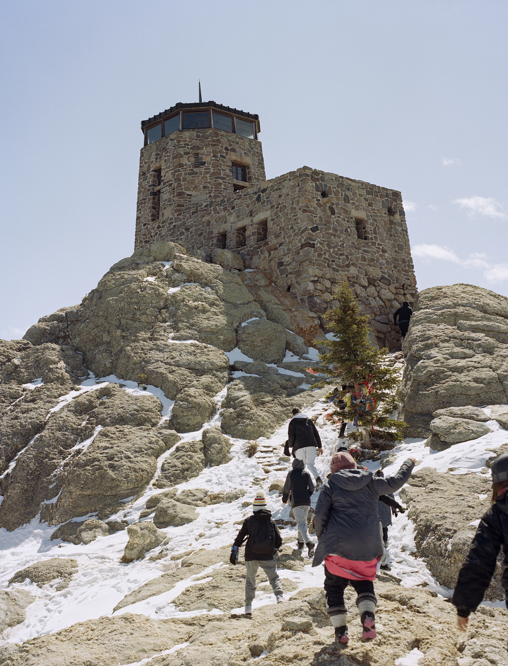 People hiking up towards a star gazing building on a rocky hill.