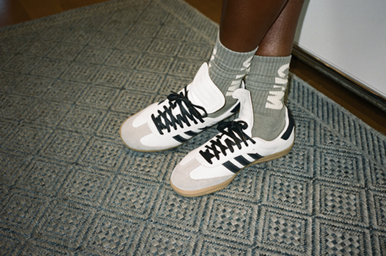 Close up of Pharrell Williams' white Adidas trainers and grey socks.