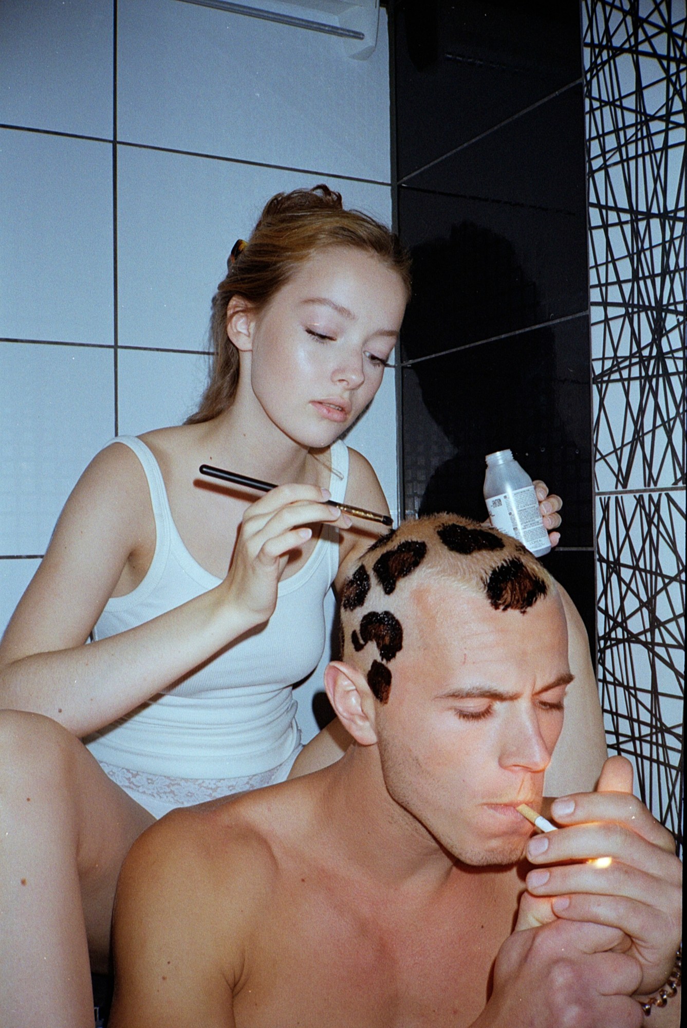 Woman painting leopard prints on man's head in inside spread of Lash Magazine