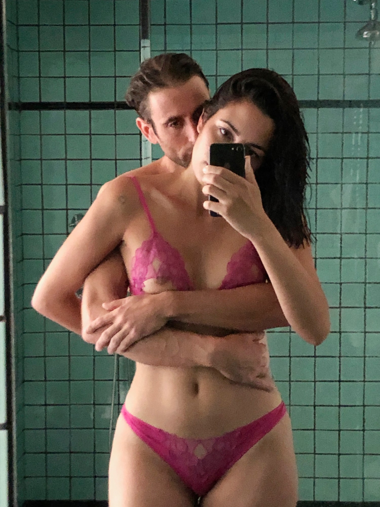 couple embracing in underwear in front of a blue tiled wall