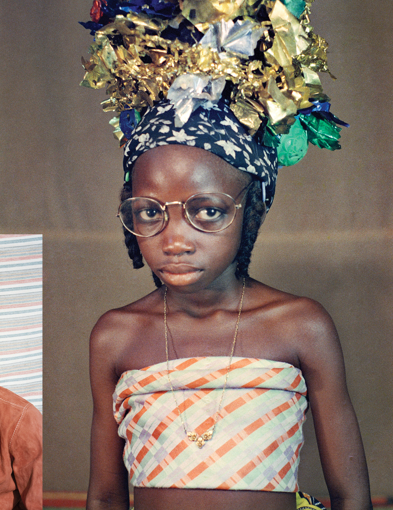 Photo of a young woman wearing a bandeau top, necklace, glasses and metallic head piece.