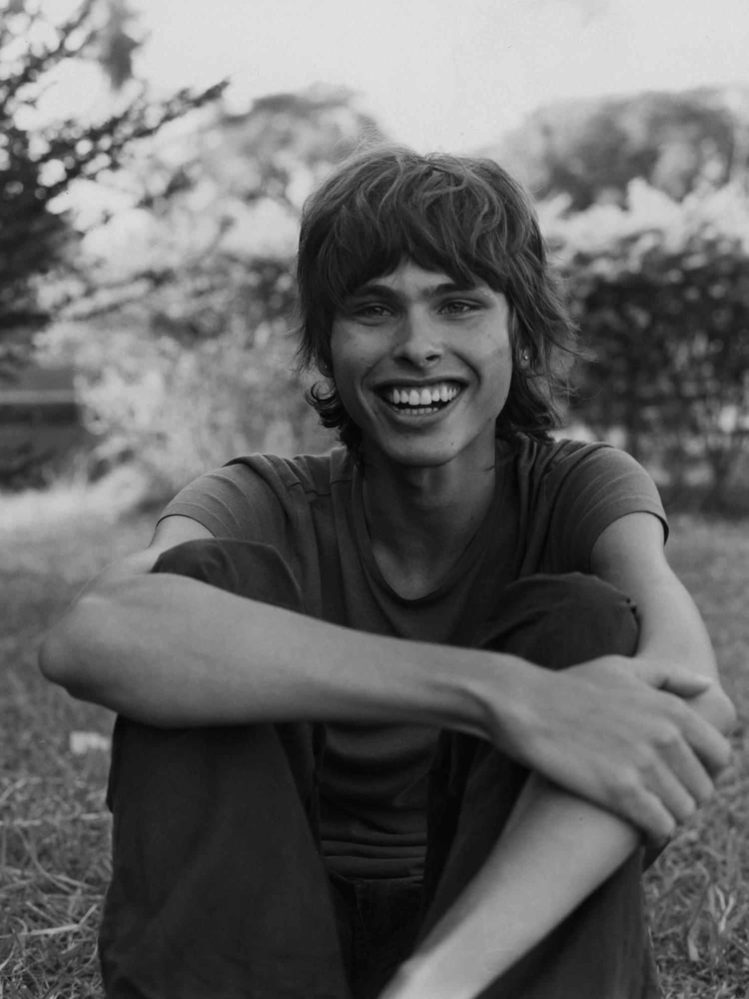 a portrait of a smiling person sitting in nature