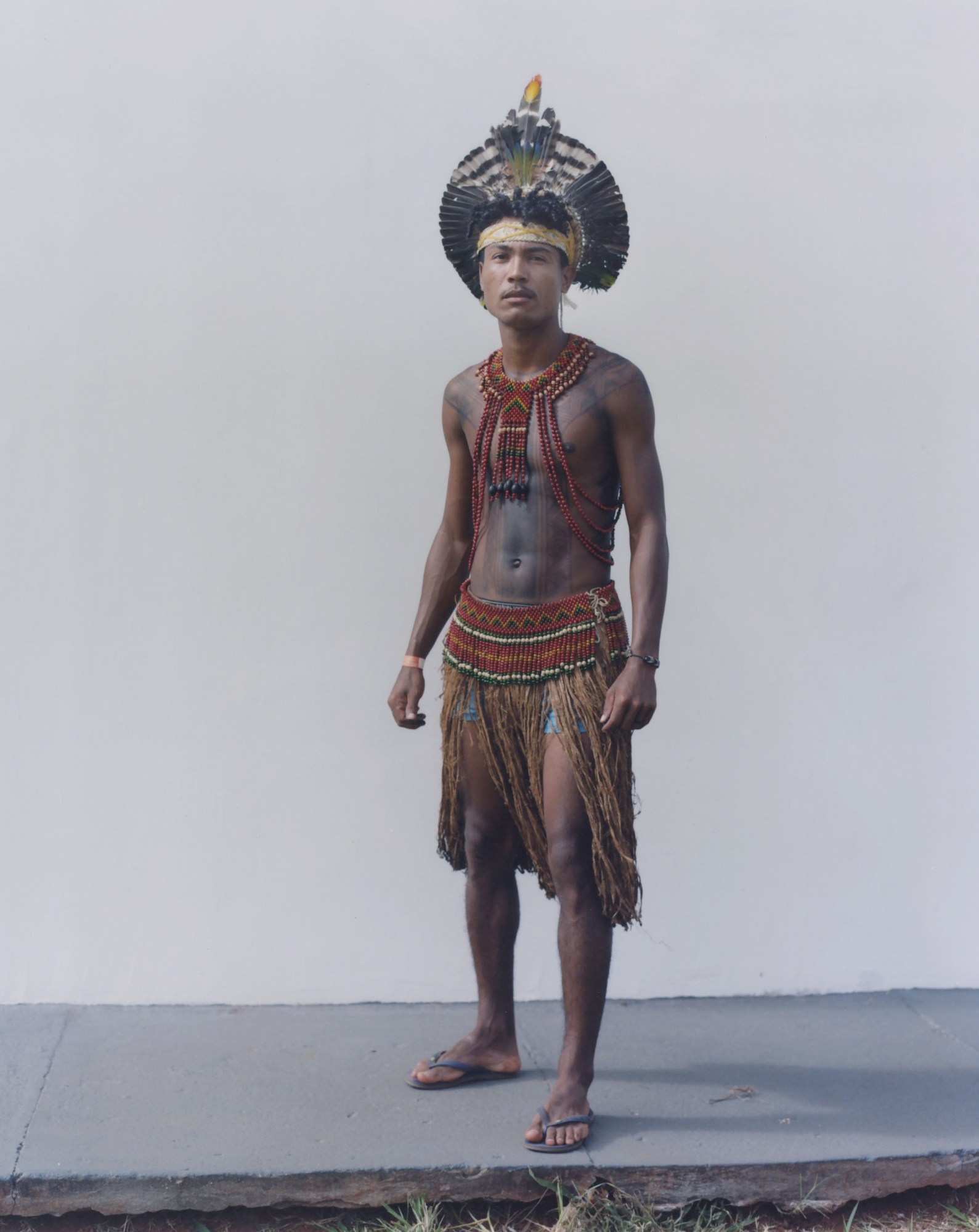 protester wearing traditional indigenous clothing standing against a wall