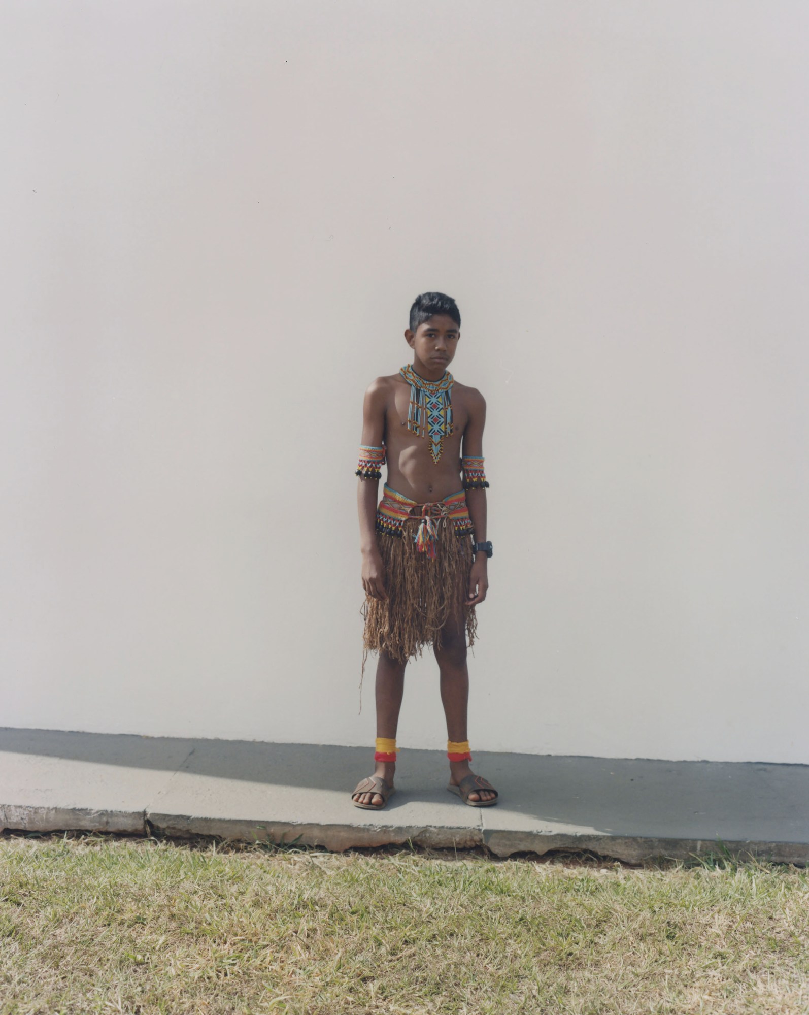 protester wearing traditional indigenous clothing standing against a wall