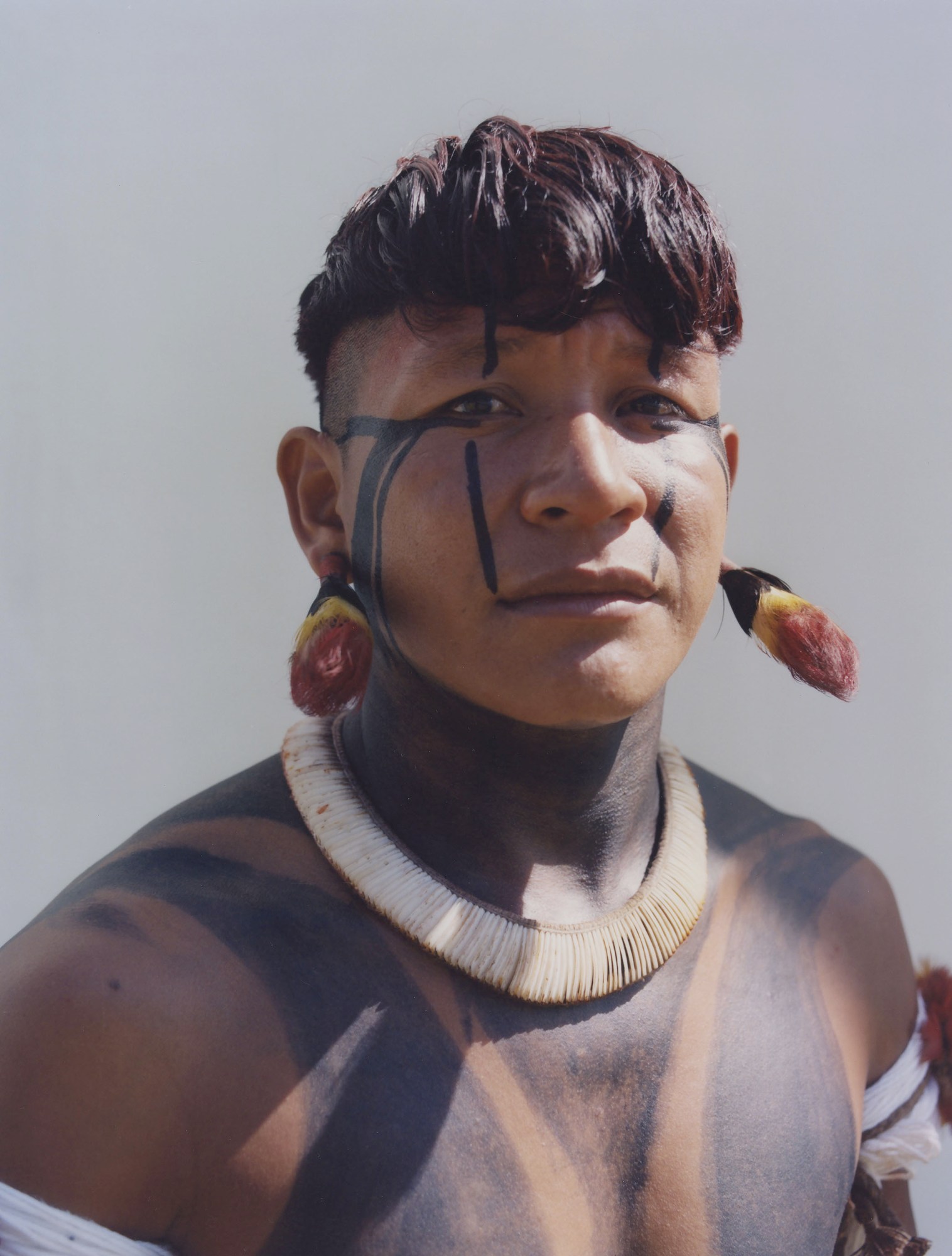 close up of protester wearing traditional indigenous clothing standing against a wall