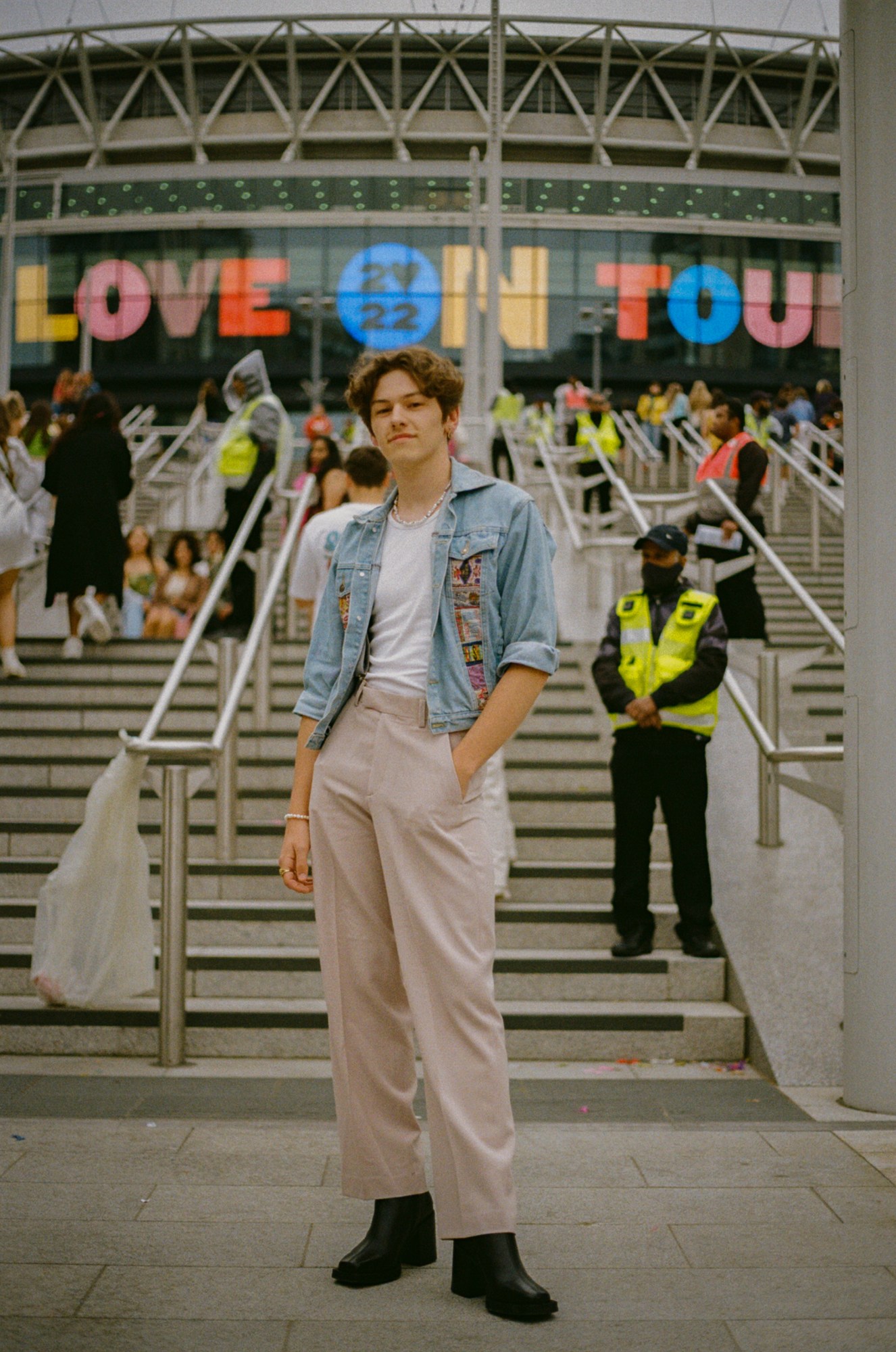 a harry styles fan in slacks, a denim jacket and a necklace