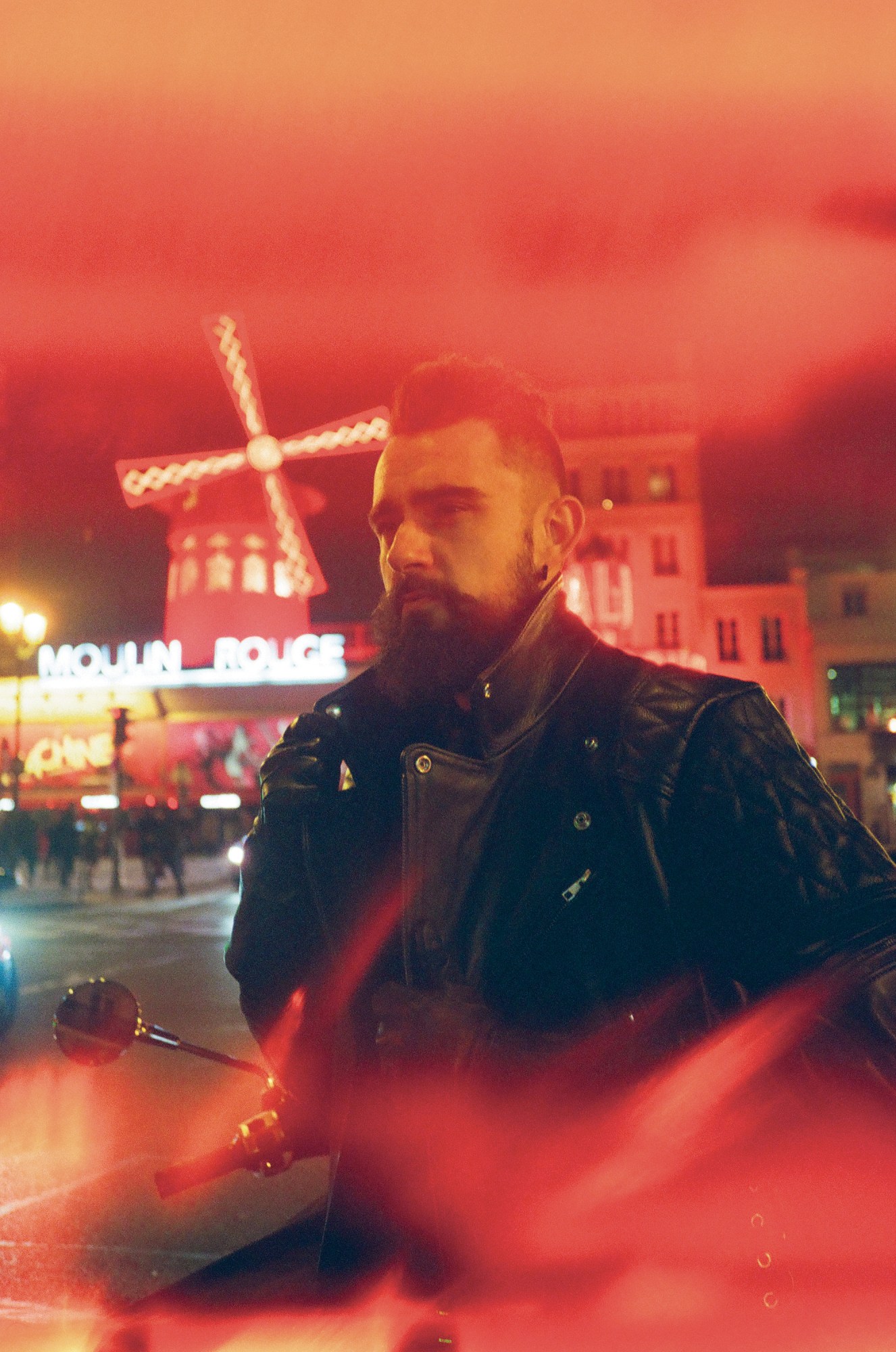 Person in full leather standing in front of the Moulin Rouge in Paris.