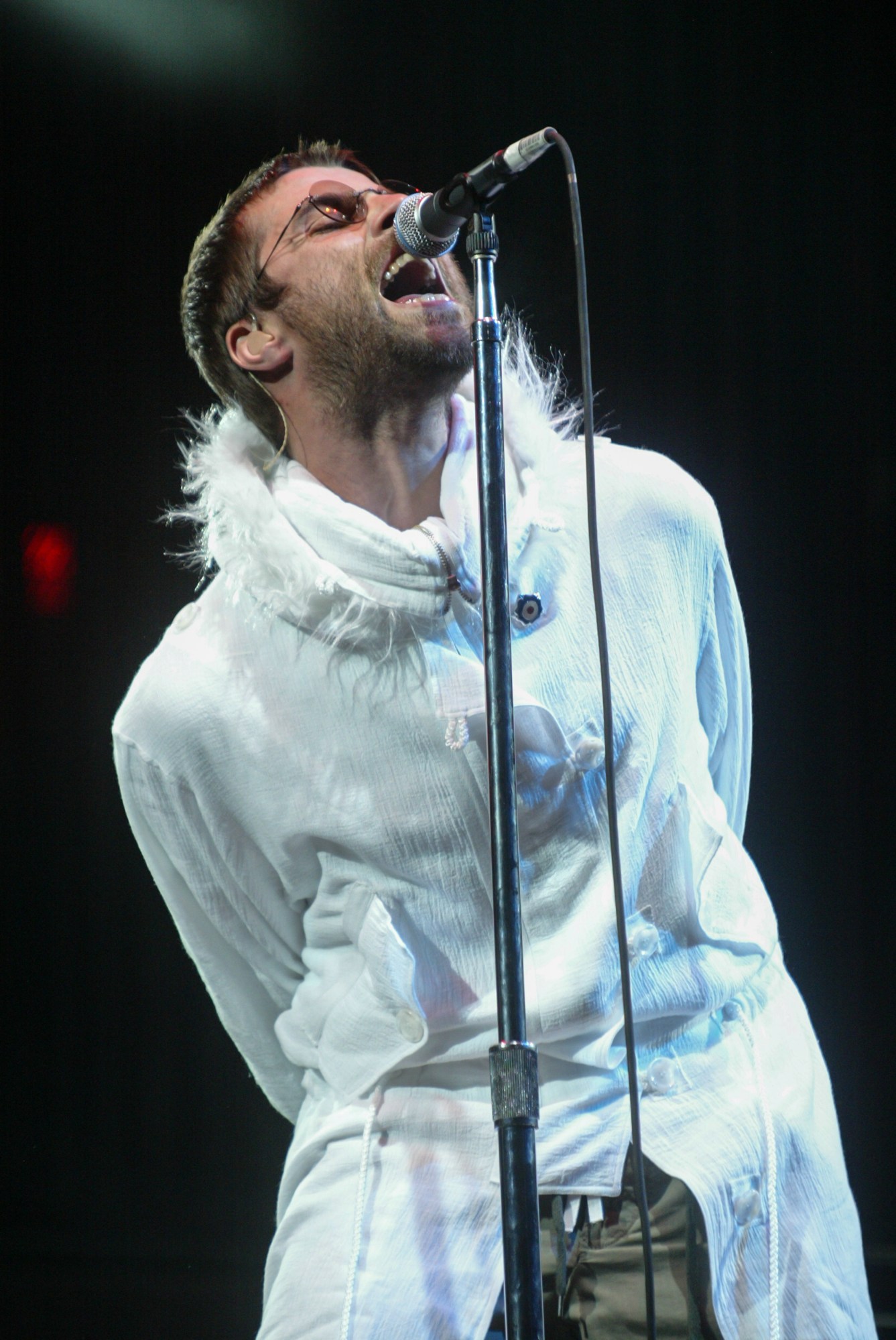 Liam Gallagher in a white feather lined anorak on the pyramid stage at Glastonbury