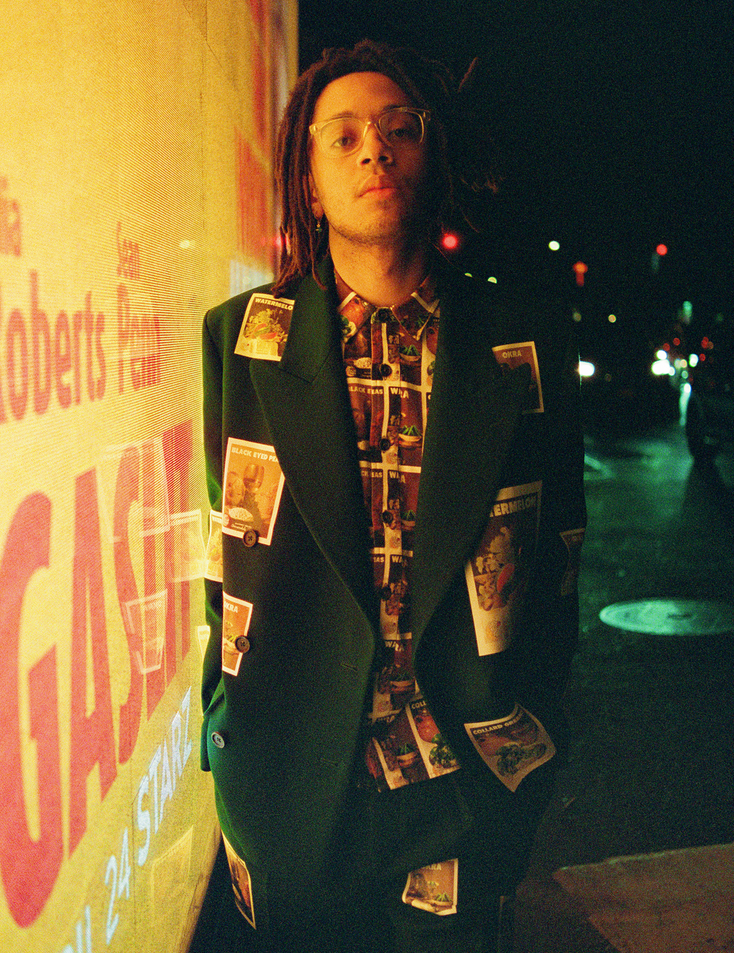 Model standing at night by a lit up billboard wearing Sky High Farm Workwear