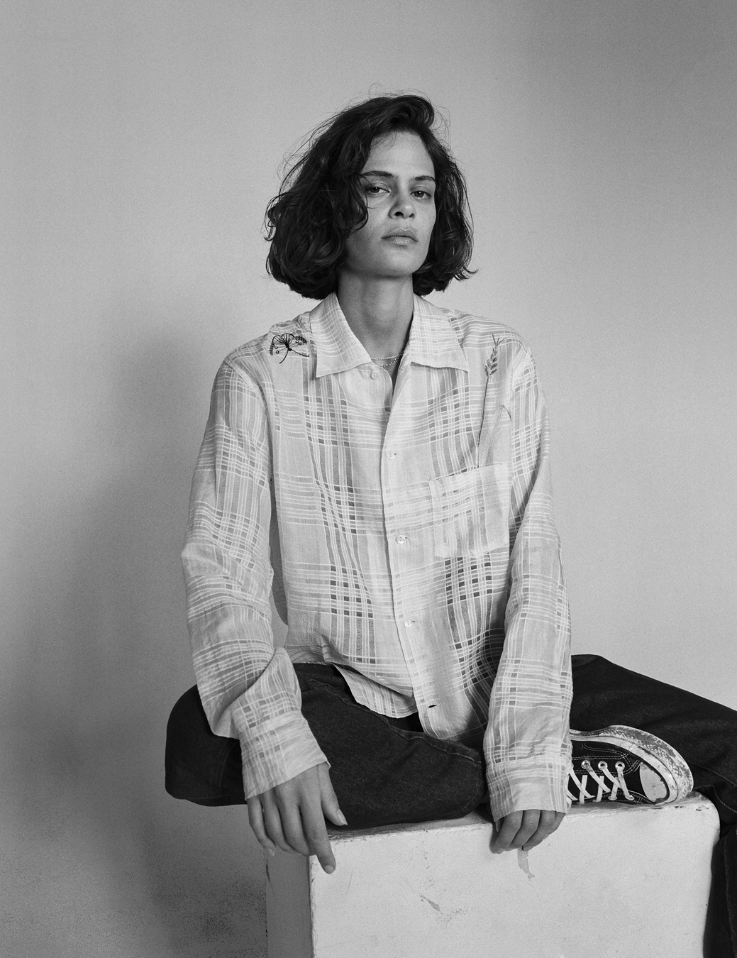 Model sitting on a slab of brick wearing Sky High Farm Workwear