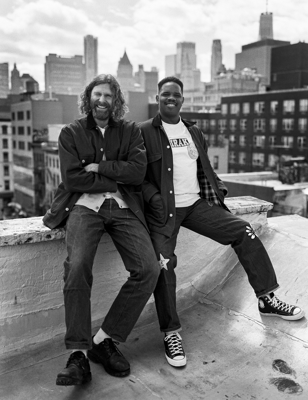 Dan and model wearing Sky High Farm Workwear sitting on a roof top skate ramp