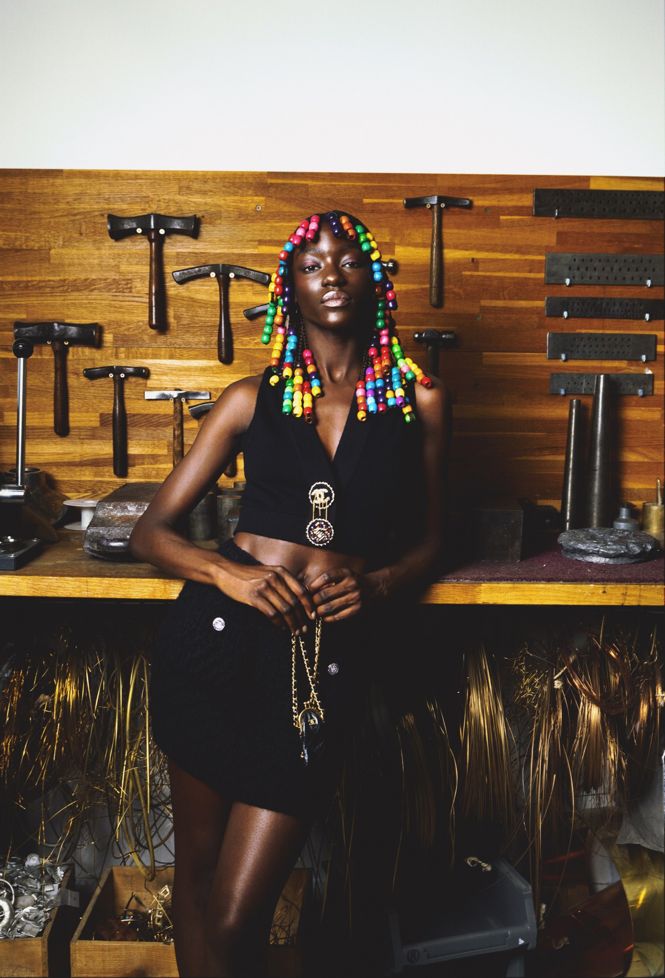 a model wears a chanel miniskirt and top combo, standing in front of a wall of workshop tools