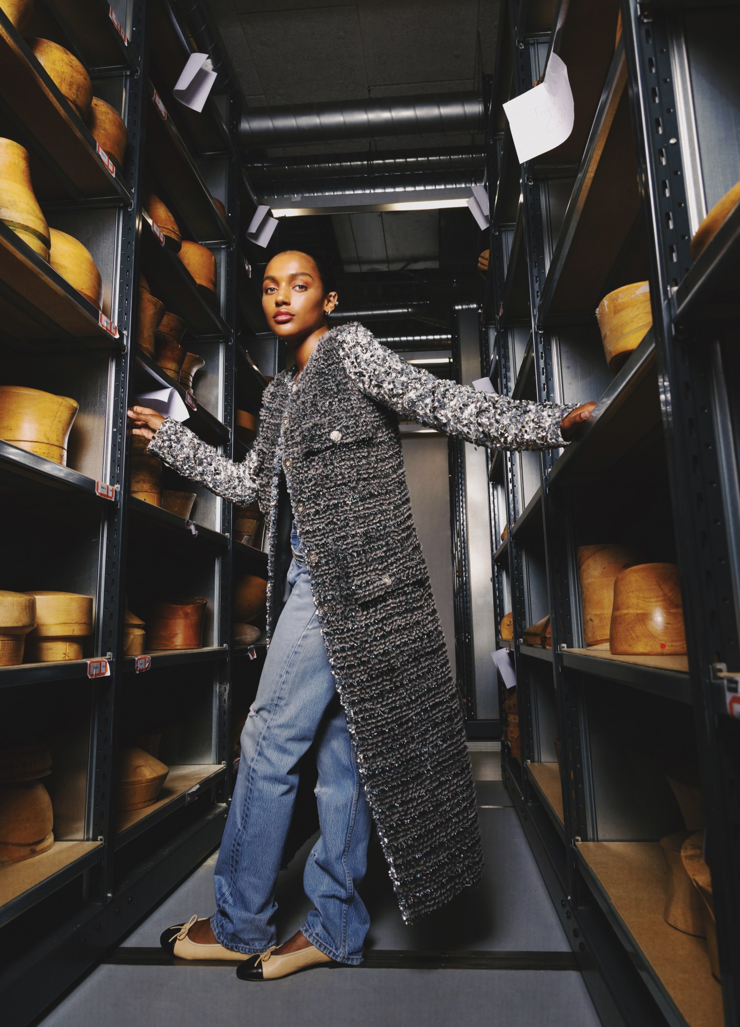 a model wears a full chanel look in a storage room of hat moulds