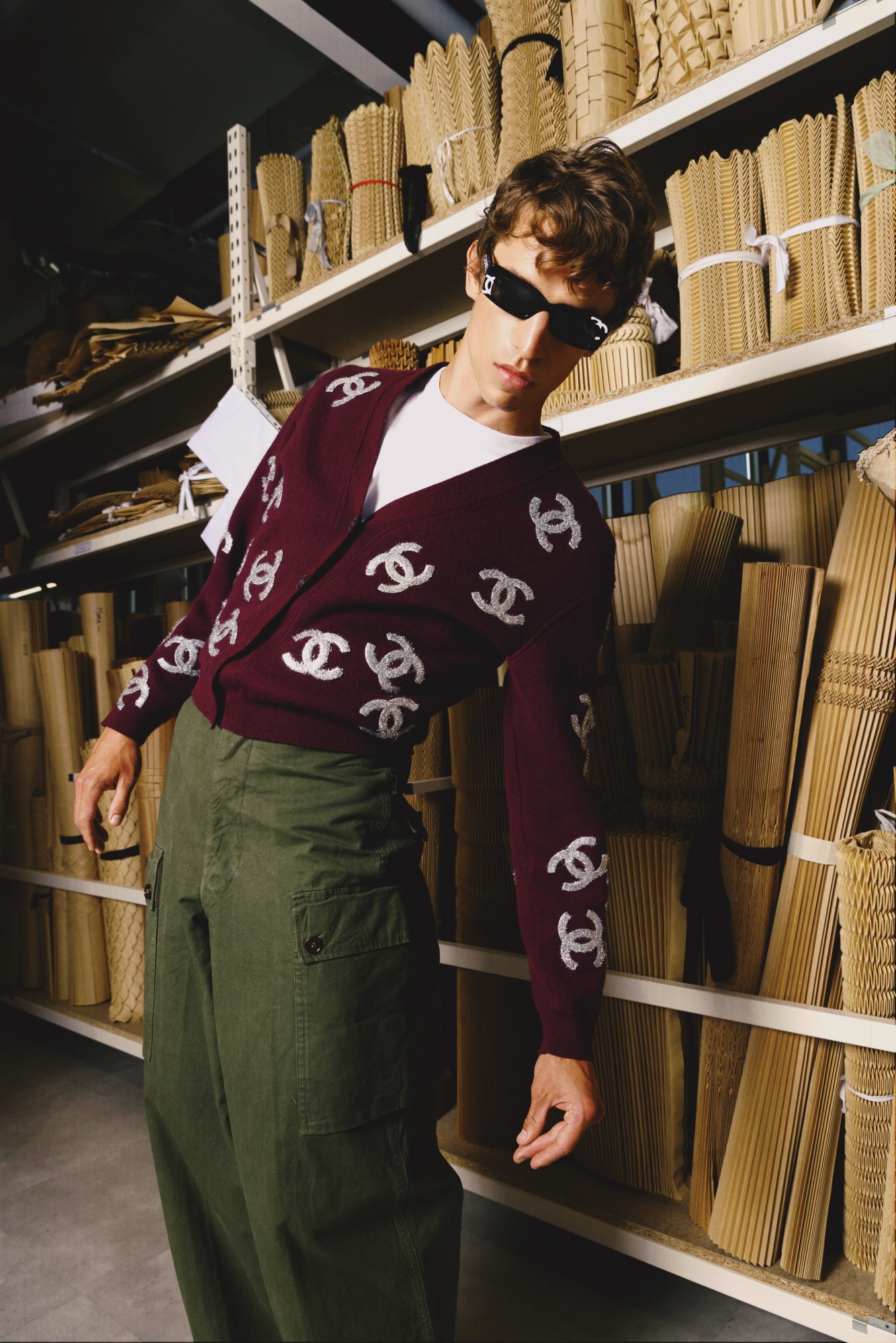 a male model poses wearing a chanel cardigan and dark sunglasses