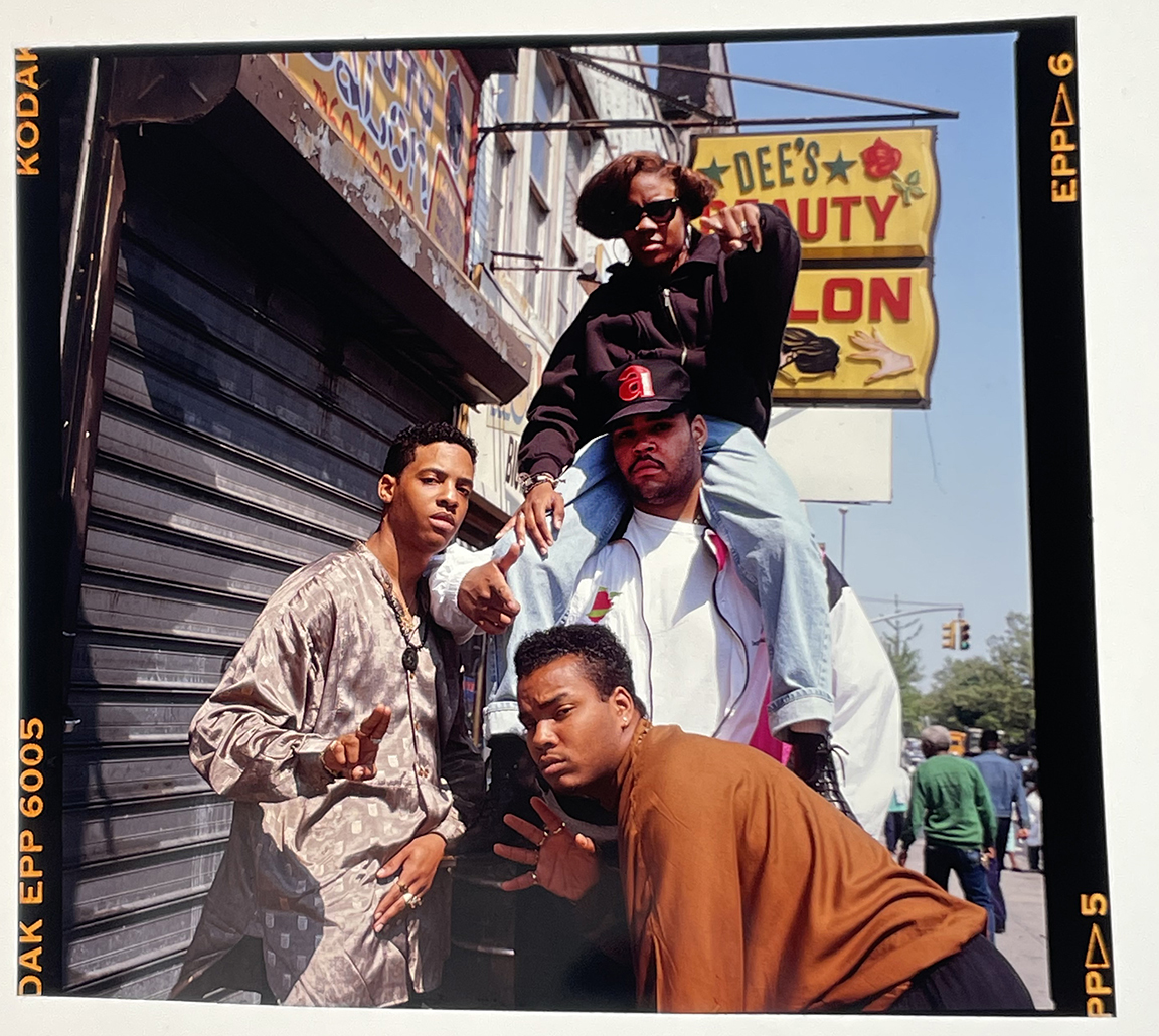 MC LYTE wearing sunglasses posing outside with others in the 90s.