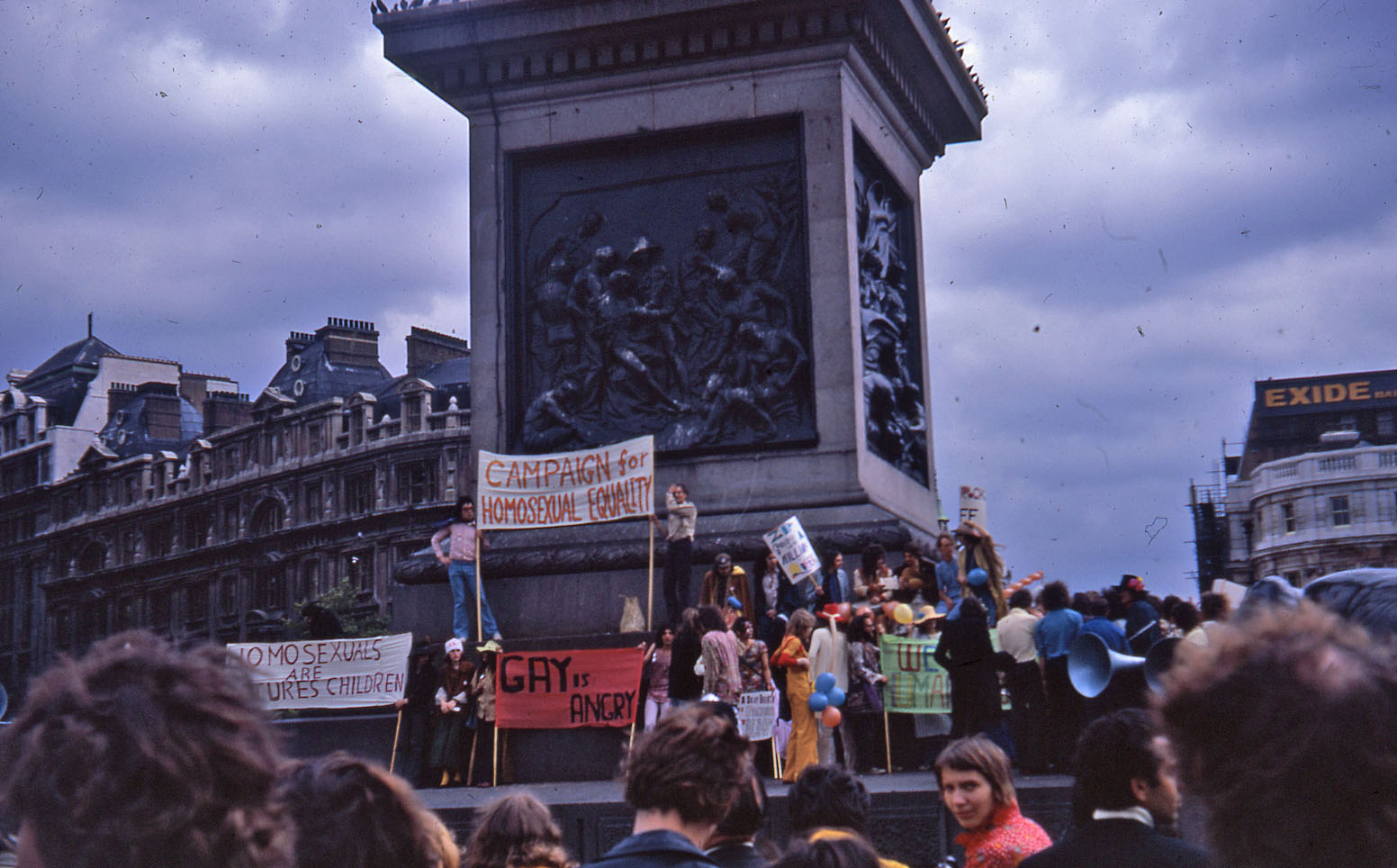 Protesters holding signs and banners on the plinth in Trafalgar Square at the 1972 pride march