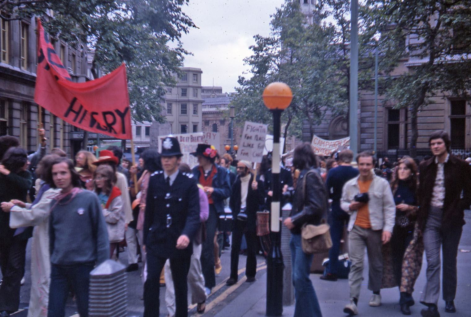 Protesters holding signs and banners walking along charring cross road on the first pride march in 1972