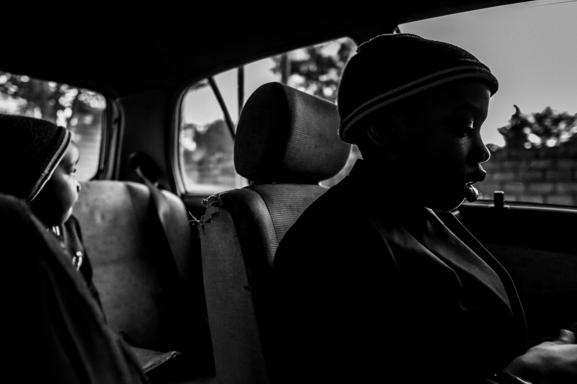 black-and-white photo of two boys sat alone in a car wearing hats