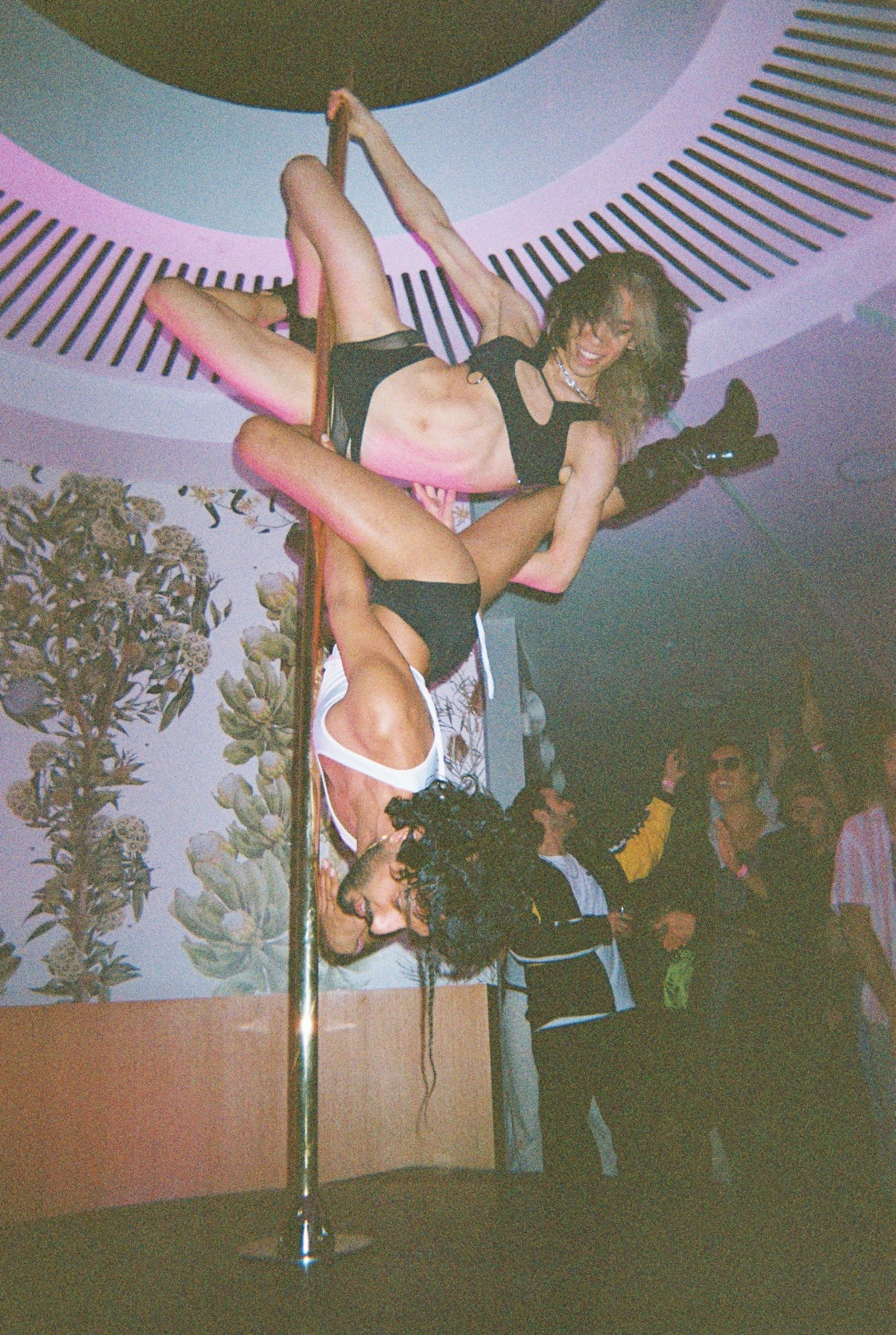 two people pole dancing on the same pole