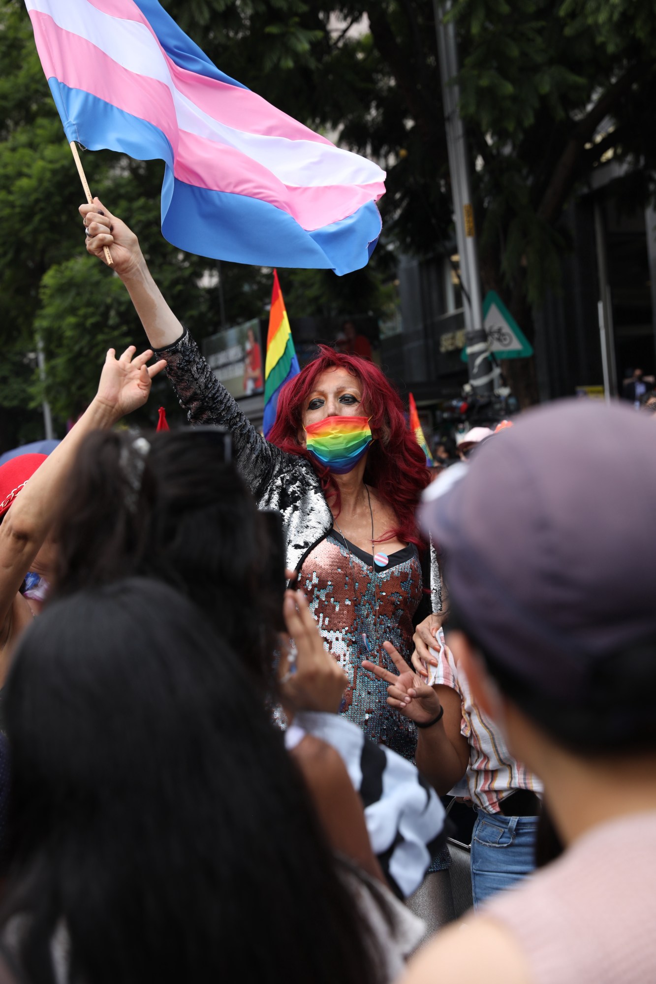 person with a gay pride mask and waving a trans flag at Mexico Pride 2022