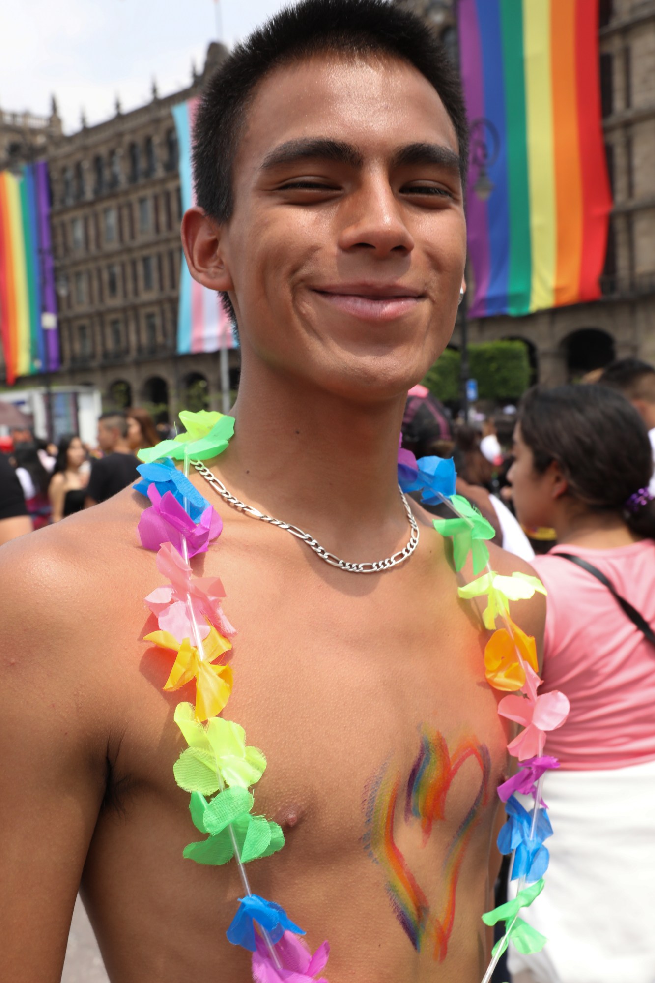 shirtless person with paint on their chest and a rainbow garland necklace at Mexico Pride 2022