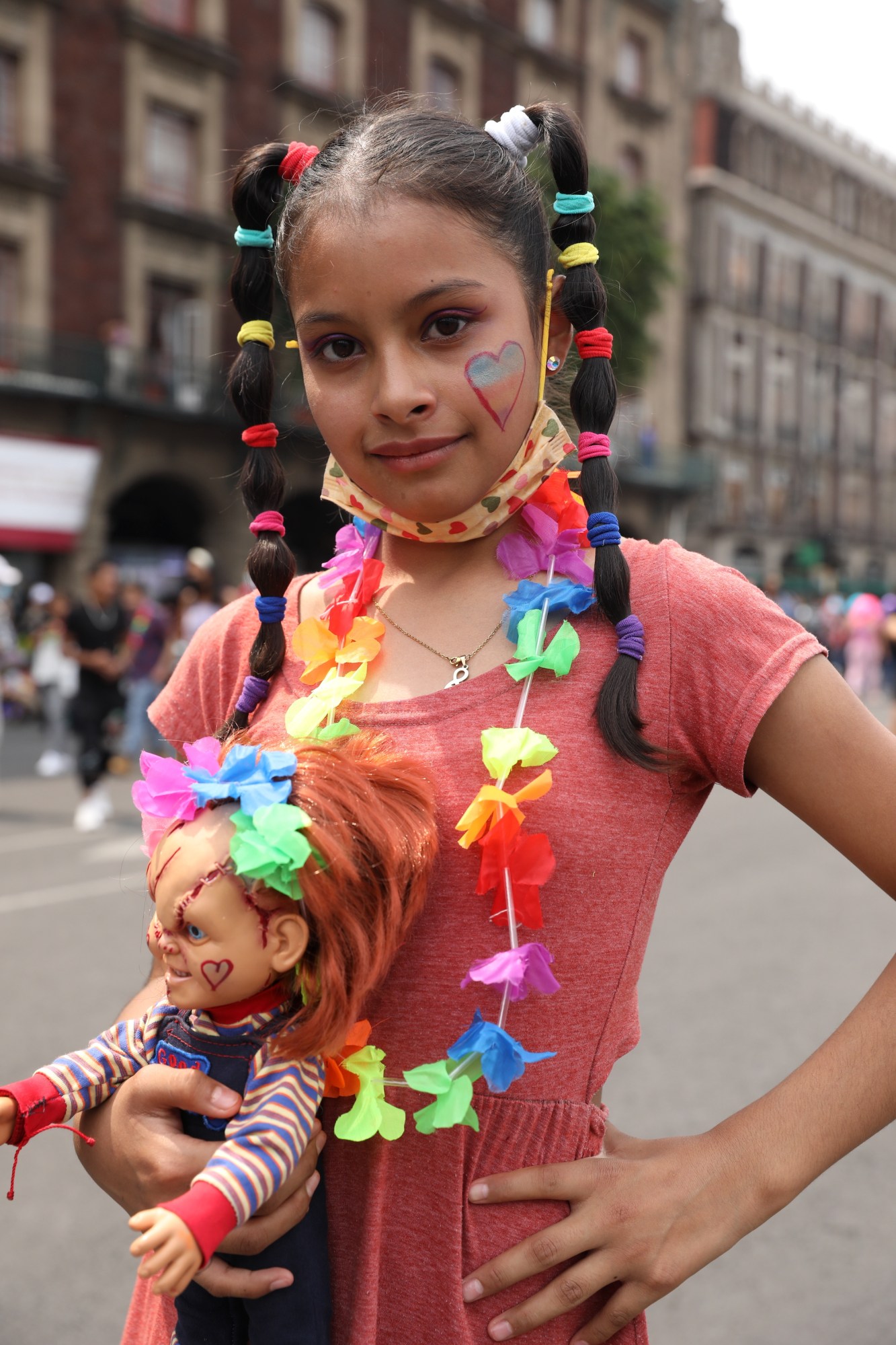 girl with a rainbow garland and a Chucky doll at Mexico Pride 2022