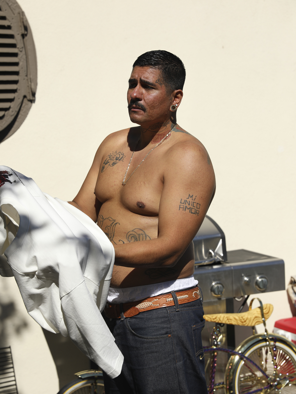 Shirtless man putting on a top standing by a bike in I-D 369 The Earthrise Issue