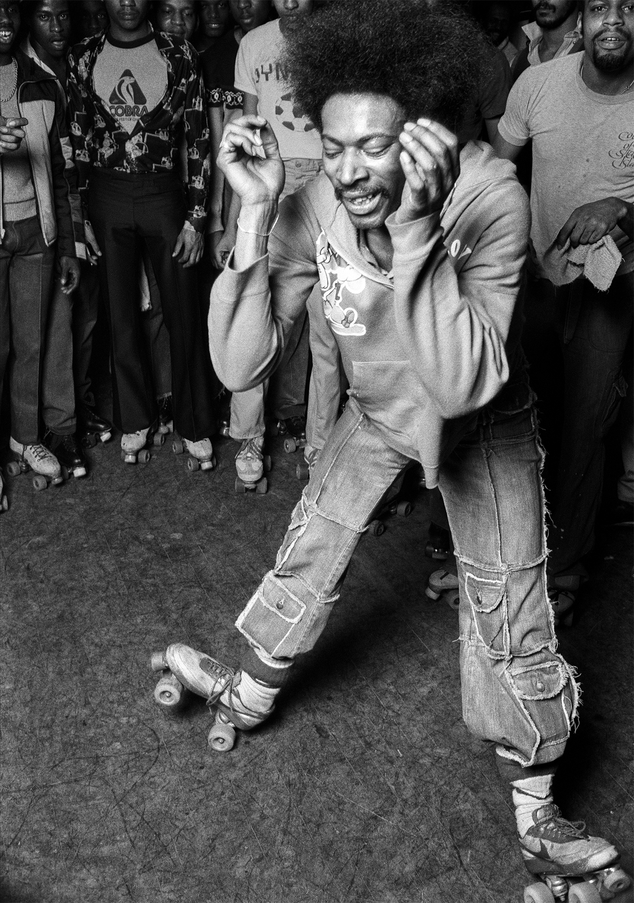 black-and-white photo of roller disco dancer in the middle of a crowd of people