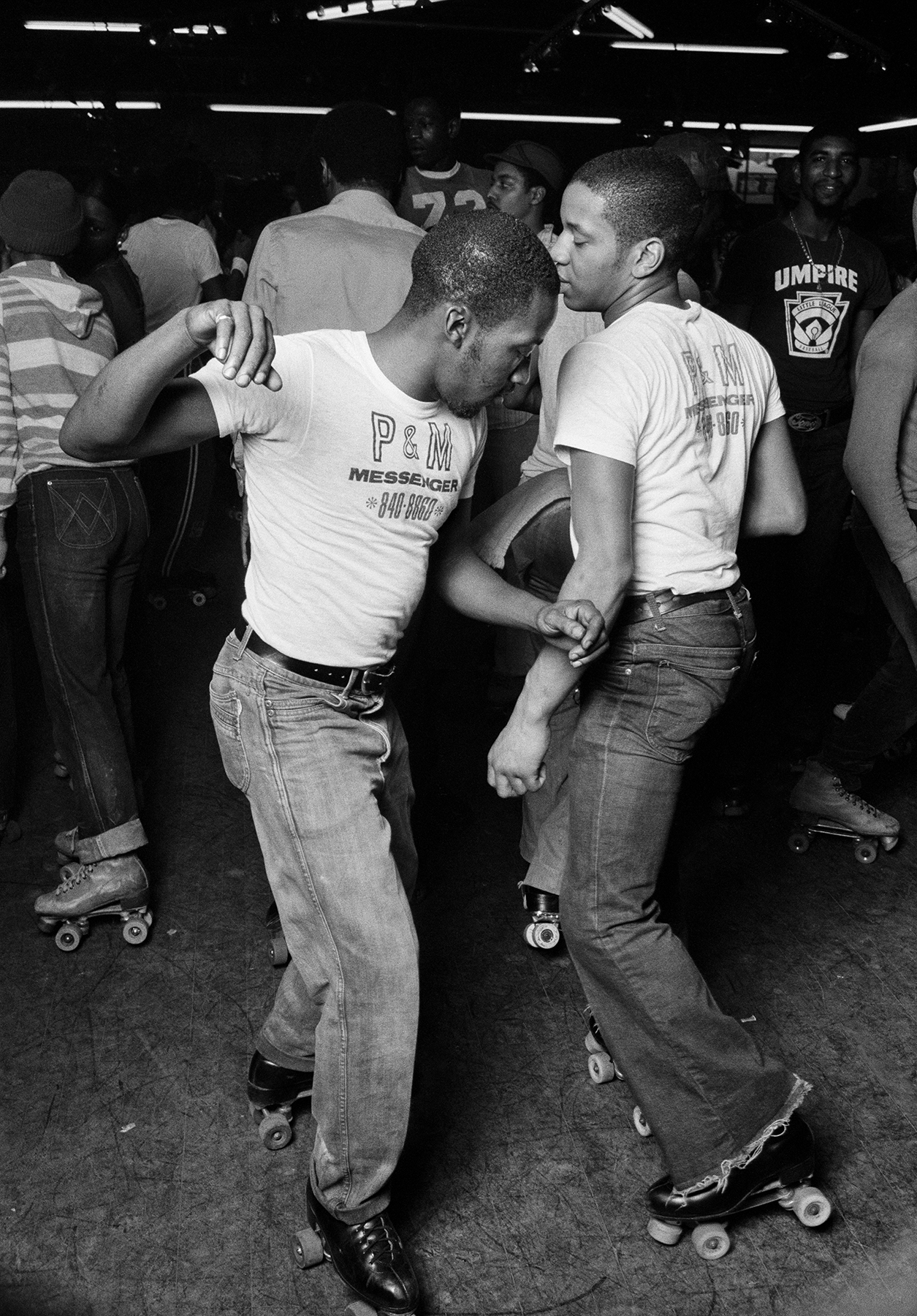 black-and-white photo of two men roller disco dancing together