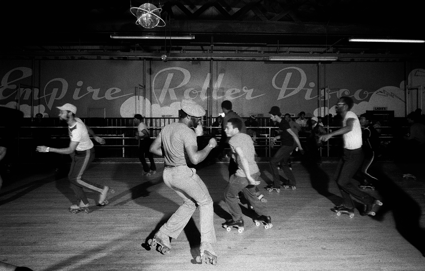 black-and-white photo of roller disco dancers spinning in a circle