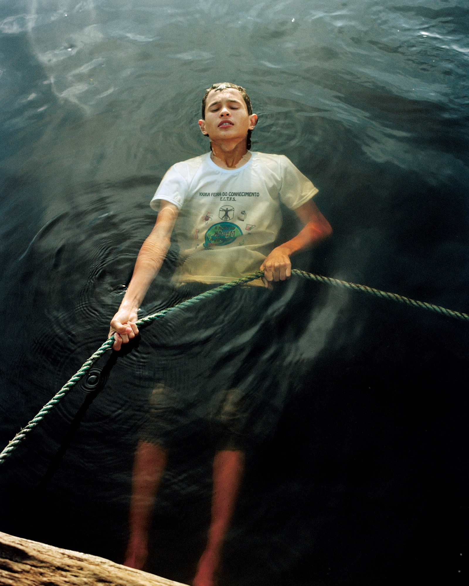 A young person pulling on a rope while submerged in water.